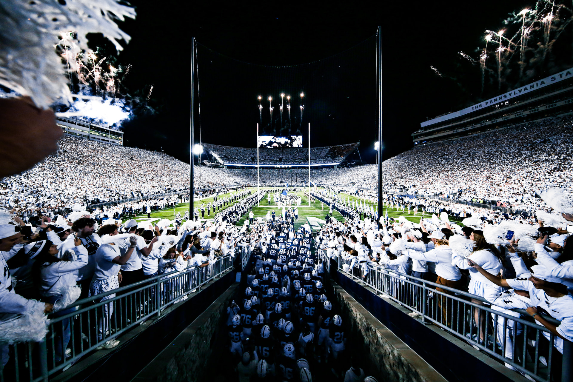 Penn State players running onto the field at a White Out game in Beaver Stadium